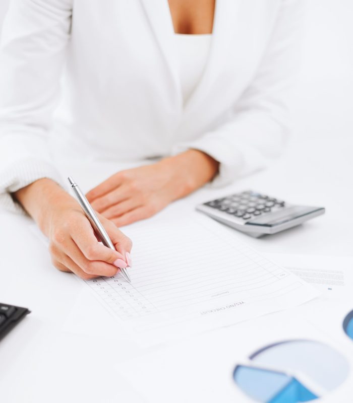 office, business, tax, accounting concept - businesswoman working with calculator in office